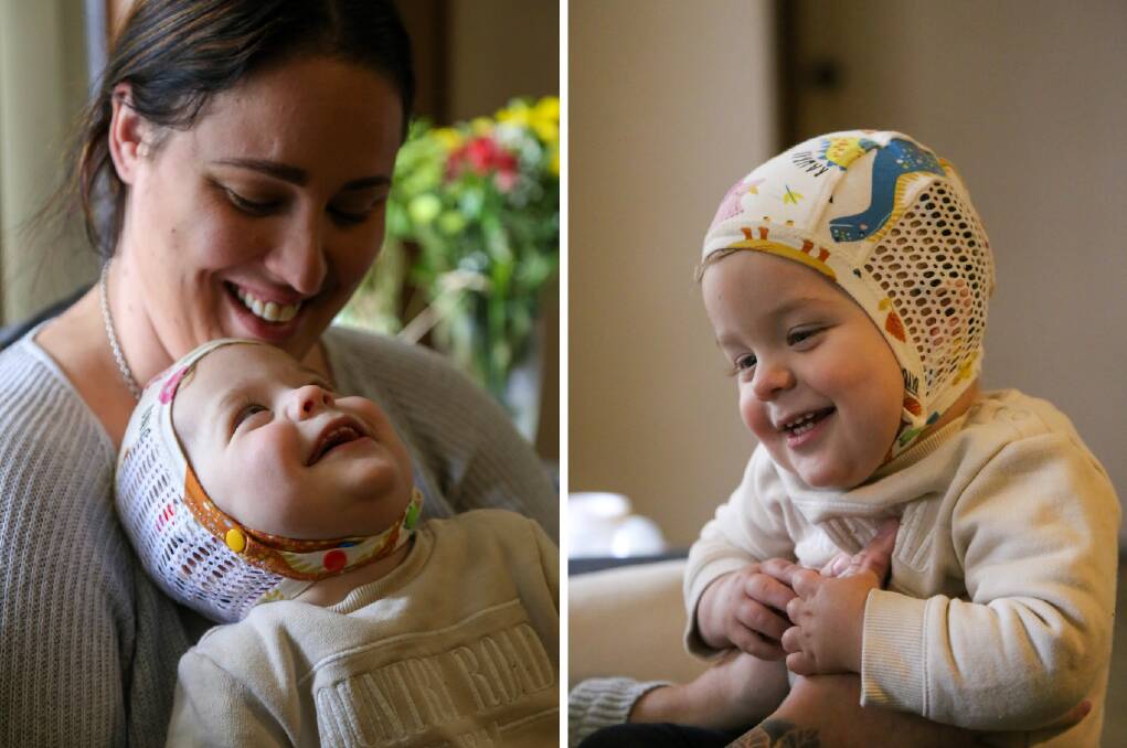 HAPPY BABY: Ari Bennett, 16 months, with mother Jamie Bennett. Ari is wearing a purpose made cap so he cannot pull out his cochlear implants. Picture: Ellie-Marie Watts