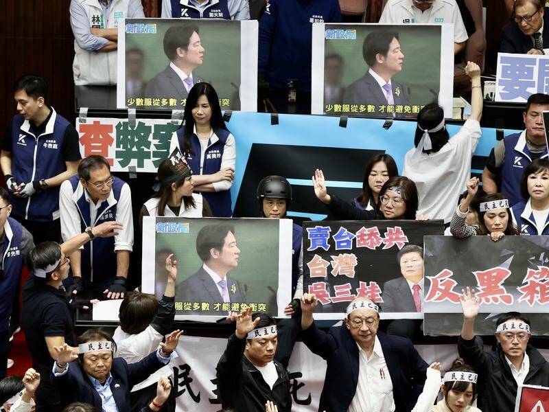 MPs held up placards of President Lai Ching-te in parliament amid debate over contentious reforms. (EPA PHOTO)