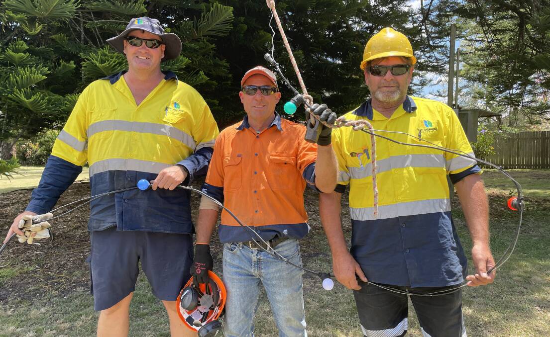 The Christmas crew that helped Dwayne Hopper install the lights are Port Stephens Council electricians Troy Atkinson and Jamie Kemp and tree ground crew Rex Hanslow (middle). Picture by Alanna Tomazin
